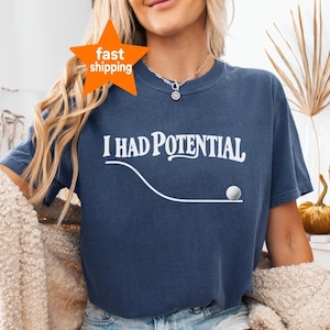 Op de afbeelding: Een marineblauw t-shirt met korte mouwen en de witte tekst I HAD POTENTIAL boven een witte gebogen lijn die eindigt in een kleine witte golfbalafbeelding. Het shirt heeft een ronde hals en een relaxte pasvorm voor een casual uitstraling.
