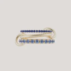 May include: A gold ring featuring three interconnected bands. The top and bottom bands are set with a row of small, round, deep blue gemstones. The middle band is a smooth, polished gold bar. The three bands are linked together by two gold loops.