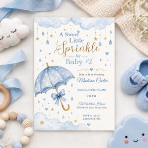 Peut inclure: Une carte d'invitation rectangulaire pour fête prénatale avec un parapluie bleu à pois, des nuages aquarelle, des étoiles dorées et des cœurs bleus. Le texte indique : A Sweet Little Sprinkle for Baby #2, Madison Carter, Saturday, October 16, 2027, 1:30 PM, The Willow House, 530 Parkview Lane, Austin, Texas, RSVP to Lauren at (555) 672-1945.