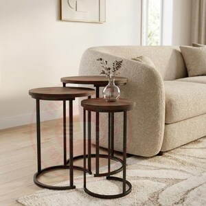 May include: A set of three nesting tables featuring dark brown circular wooden tops and thin black metal frames. The tables are arranged in a tiered formation with a clear glass vase containing dried stems placed on the tallest table surface.