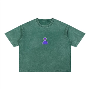 Könnte beinhalten: Ein kurzärmeliges T-Shirt in einem dunklen, mineralisch gewaschenen Waldgrün. Das Shirt hat einen Rundhalsausschnitt und eine kleine, zentrierte Grafik einer violetten Alien-Figur mit leuchtend orangefarbenen Augen im oberen Brustbereich.