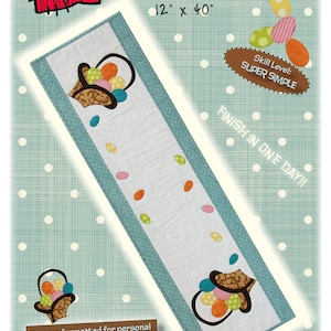 Könnte beinhalten: Ein blauer und weißer Tischläufer mit einem Korb voller bunter Eier und dem Text "Bunny Basket Table Runner 12" x 40" MM904 Schwierigkeitsgrad: SUPER EINFACH IN EINEM TAG FERTIG !! Muster für persönliche Schneidemaschinen formatiert Patch Abilities, Inc."