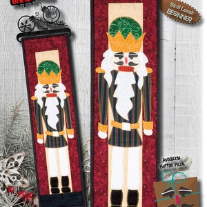 May include: A Nutcracker quilt pattern with a red, white, and blue color scheme. The pattern is for a 6 inch by 23 inch wall hanging. The pattern is labeled "P98" and is for beginners.