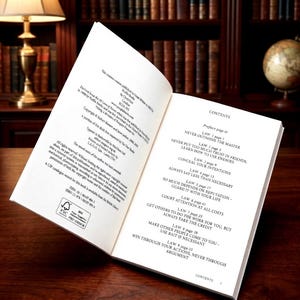 Pu&ograve; includere: Un libro con copertina rigida aperto con pagine bianche e testo nero. La pagina sinistra mostra le informazioni sul copyright e i dettagli di pubblicazione. La pagina destra mostra un indice che elenca nove leggi, tra cui Never Outshine the Master e Conceal Your Intentions.