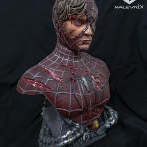 May include: A detailed bust of a character wearing a damaged red and black spider-web patterned suit with exposed human skin and hair on one side. The chest features a spider emblem and deep gashes. Metallic mechanical tentacles wrap around the base.