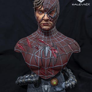 May include: A detailed bust of a character with a half-exposed human face and a half-masked spider-themed suit. The suit is dark red with a black web pattern, battle damage, and a central spider emblem. Metallic mechanical tentacles wrap around the base.