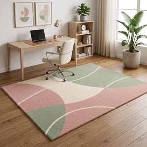 May include: A rectangular area rug featuring a geometric pattern of overlapping circles and curved lines in muted shades of dusty rose pink, sage green, and cream. The rug has a low-pile texture and is positioned on a light-toned wooden floor.
