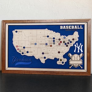 Peut inclure: Une décoration murale rectangulaire avec un cadre en bois, présentant une carte des États-Unis en bois clair sur un fond bleu profond. La carte affiche des emplacements de stades de baseball avec des marqueurs, le texte BASEBALL et Yankees.
