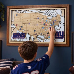 May include: A rectangular wooden wall map of the United States featuring state outlines, stadium locations, and the text Giants. The map includes layered cutouts of footballs and an American flag design, framed in dark wood with a light wood border.