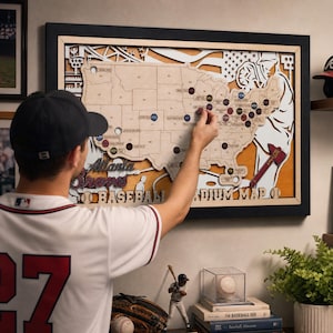 Puede incluir: Un mapa de madera enmarcado de los Estados Unidos con ubicaciones de estadios de béisbol, con el texto Atlanta Braves Baseball Stadium Map. El mapa incluye un recorte de un jugador de béisbol, un bate y un diseño de bandera estadounidense.