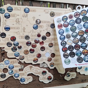 May include: A wooden map of the United States featuring engraved state outlines and national park names, accompanied by a sheet of circular stickers depicting various national parks to be placed on the corresponding map locations.