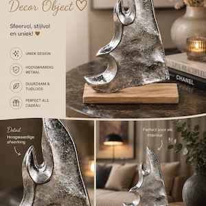 Op de afbeelding: Een zilverkleurig abstract beeldhouwwerk met een getextureerde, metalen afwerking op een rechthoekige houten voet. Het object heeft gebogen, vlamachtige randen en een gepolijst, reflecterend oppervlak als decoratief item.