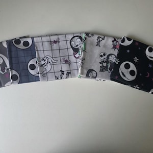 May include: Five folded fabric squares featuring characters and motifs from The Nightmare Before Christmas. Patterns include Sally on a gray background, Jack Skellington on blue plaid, Zero on a grid, various characters on white, and Jack on black.
