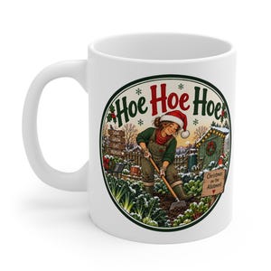 May include: A white ceramic mug featuring a circular illustration of a person in a Santa hat gardening in the snow. The text reads Hoe Hoe Hoe, Sow Grow Eat Repeat, and Christmas on the Allotment. The scene includes a shed and winter plants.