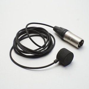 May include: A black circular microphone transducer attached to a thin black cable that coils into a circle and terminates in a silver-colored three-pin XLR connector. The microphone component is matte black and cylindrical in shape.