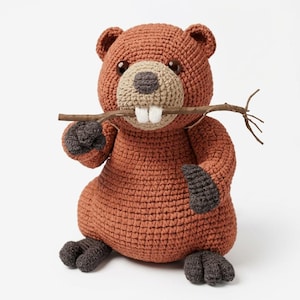 May include: A crocheted beaver stuffed animal with rust-colored yarn, dark gray paws and feet, a light tan muzzle, and two prominent white teeth. The beaver is holding a thin, natural brown wooden twig horizontally in its mouth.