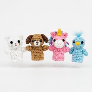 May include: A set of four crocheted finger puppets featuring a white cat with pink stitched details, a brown dog with floppy ears, a pink unicorn with a yellow horn and purple mane, and a light blue bird with a yellow beak and blue tuft.
