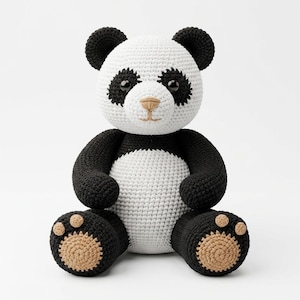 Pode incluir: Um brinquedo de panda em crochê feito à mão com cabeça e tronco brancos, além de orelhas, manchas nos olhos, braços e pernas pretos. O panda possui olhos de plástico preto brilhante, nariz e boca bordados em bege e solas bege nos pés.