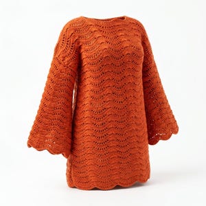May include: A long-sleeved sweater in a vibrant burnt orange color, crafted with a detailed crochet wave pattern throughout. The garment features a rounded neckline and wide, flared sleeves with a scalloped edge finish at the cuffs and hem.