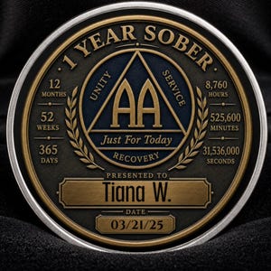 May include: A circular 1 Year Sober recovery medallion with gold and dark blue accents. The coin features the AA triangle, the text 1 Year Sober, Unity, Service, Just For Today, Recovery, Tiana W., and the date 03/21/25, plus time increments.