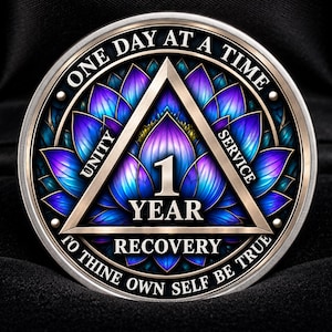 Op de afbeelding: Een ronde herstelmedaille met een centrale driehoek met de tekst 1 YEAR, omringd door een levendig paars en blauw lotusbloemmotief. De buitenrand bevat de tekst ONE DAY AT A TIME en TO THINE OWN SELF BE TRUE.