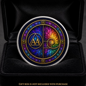 May include: A circular medallion featuring a vibrant, multi-coloured spiral pattern on the right and a blue background with the letters AA inside a triangle on the left. The design is framed by a gold border with small circular accents.