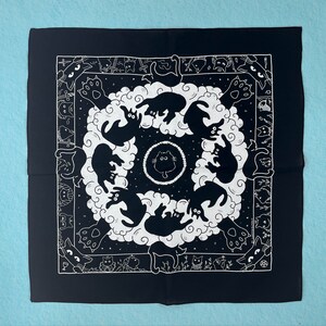 Puede incluir: Bandana negra y blanca con un patr&oacute;n repetitivo de gatos en c&iacute;rculo. Los gatos est&aacute;n todos mirando hacia adentro y tienen un dise&ntilde;o estilizado. La bandana est&aacute; hecha de una tela de algod&oacute;n suave.