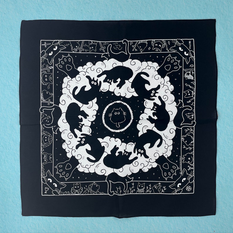 Puede incluir: Bandana negra y blanca con un patr&oacute;n repetitivo de gatos en c&iacute;rculo. Los gatos est&aacute;n todos mirando hacia adentro y tienen un dise&ntilde;o estilizado. La bandana est&aacute; hecha de una tela de algod&oacute;n suave.
