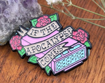 May include: Enamel pin with the text "IF THE APOCALYPSE COMES" on a pink banner, surrounded by red roses and green leaves. A digital clock is at the bottom. The pin has a black outline.