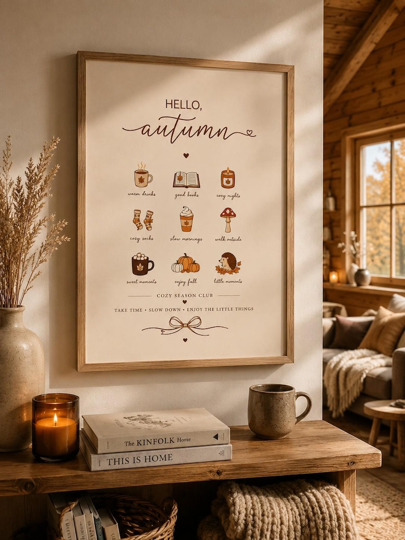 May include: A framed wall art print with a cream background featuring the text HELLO, autumn and a grid of nine small illustrations including a mug, book, candle, socks, coffee, mushroom, cocoa, pumpkins, and hedgehog with the text COZY SEASON CLUB.