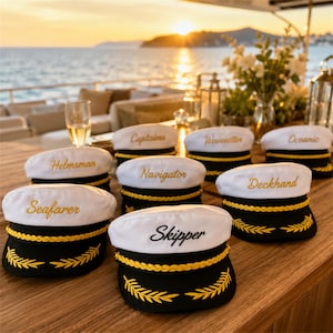 May include: A collection of white and black nautical caps featuring gold embroidered trim and gold lettering. Each cap displays a unique title including Seafarer, Helmsman, Captains, Navigator, Skipper, Wavesetter, Deckhand, and Oceanic.