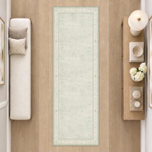 May include: A rectangular runner rug featuring a pale sage green field with a distressed, faded appearance. The rug is decorated with a subtle, repeating geometric diamond pattern and a wide border containing intricate, small-scale floral motifs.