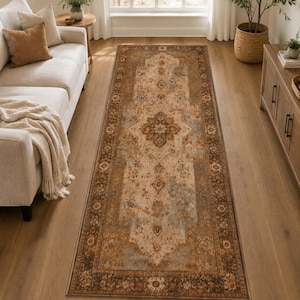 May include: A rectangular runner rug featuring a central medallion and intricate floral patterns in shades of brown, beige, and muted blue. The rug has a wide, dark brown border with repeating floral motifs, creating a balanced and symmetrical design.