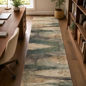 May include: A long rectangular area rug featuring a horizontal abstract pattern in muted shades of sage green, charcoal gray, and beige. The design includes subtle, delicate botanical illustrations of thin stems and leaves layered over the brushstrokes.