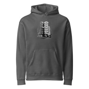 May include: A charcoal gray hooded sweatshirt featuring a central graphic print of the Dancing House building in Prague. The design is rendered in black and white with architectural line details, set against the solid dark gray fabric of the hoodie.