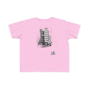 May include: A light pink short-sleeve t-shirt featuring a black and white graphic illustration of a multi-story building with curved architectural lines. The design includes thin geometric lines, dots, and the text ACA printed in a small triangle.