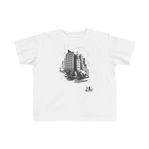 May include: A white short-sleeve t-shirt featuring a black and white graphic print of a stylized building with geometric lines and a circle. The design includes a small logo at the bottom right with the text ACA in a triangular frame.