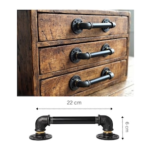 Può includere: Una cassettiera in legno a tre cassetti con maniglie in tubo di metallo nero. Il design della maniglia è composto da una sezione centrale tubolare collegata a due flange di montaggio circolari. La maniglia misura 22 cm di lunghezza e 6 cm di altezza.