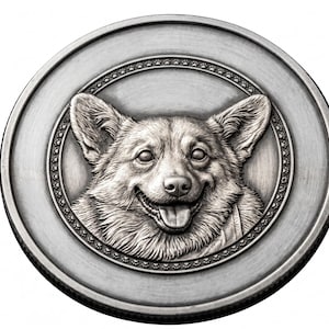 Op de afbeelding: Een ronde zilverkleurige metalen munt met een gedetailleerd reliëfportret van een Corgi-hond met de tong uit de bek. De hond is gecentreerd binnen een cirkelvormige rand versierd met een herhalend patroon van kleine pootafdrukken.