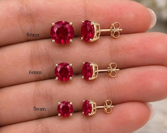 Puede incluir: Tres pares de pendientes de botón con piedras preciosas rojas de corte redondo montadas en metal dorado. Los pares están etiquetados con los tamaños 8mm, 6mm y 5mm. Cada pendiente presenta un engaste de cuatro garras y un cierre de poste.