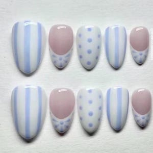 May include: A set of ten press-on nails featuring a mix of designs including light blue and white vertical stripes, light blue polka dots on a white base, and a French manicure style with a nude base and light blue floral accents at the tips.
