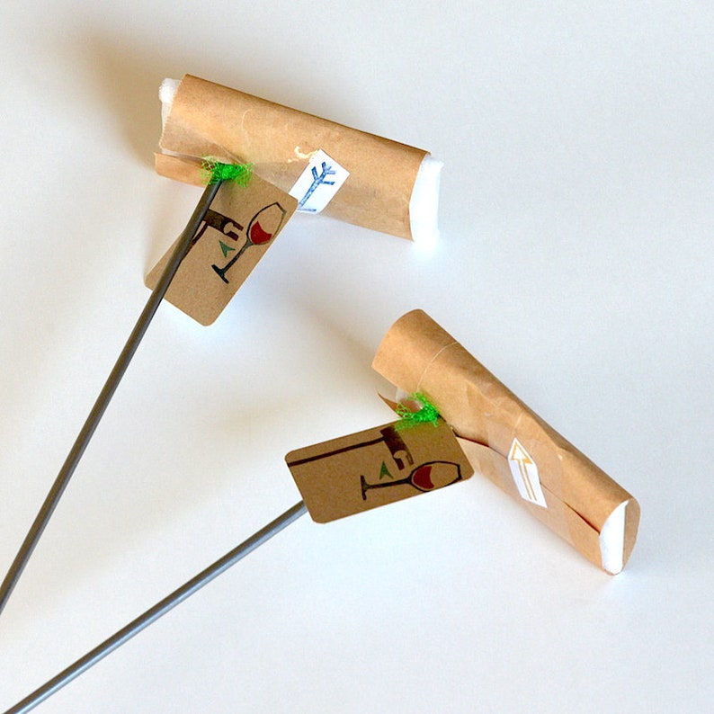 May include: Two brown paper wrapped wine bottle stoppers with green string and a wine glass icon on a brown tag attached to a silver metal rod.