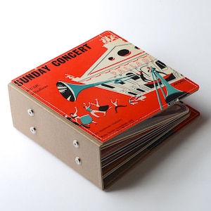 May include: A vintage-style album with a red cover featuring the words "SUNDAY CONCERT" and an illustration of a musical performance. The album has a tan, rectangular body with silver rivets and contains multiple pages.