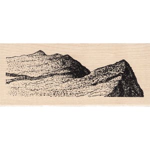 May include: A black and white line drawing of a mountain range on a wooden background.