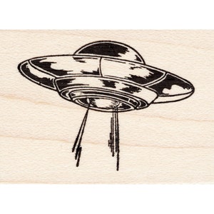 May include: A black and white illustration of a flying saucer with beams of light shooting out from the bottom.