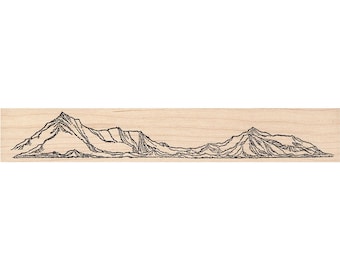 May include: A wooden stamp featuring a detailed black line drawing of a mountain range. The design includes peaks, valleys, and varying textures, creating a landscape scene. The stamp is rectangular and made of light-colored wood.
