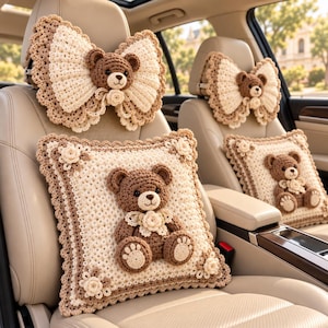 May include: A set of cream and brown crochet car accessories including two bow-shaped headrest covers and two square pillows, each featuring a central brown teddy bear appliqué with a small cream flower accent and scalloped edges.