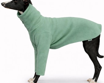 May include: A sage green fleece dog sweater with a high turtleneck collar and long sleeves. The garment features a soft, solid-colored fabric construction that covers the torso and front legs, with a small rectangular brand tag on the side.