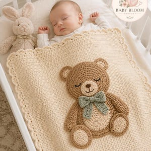 Puede incluir: Una manta de bebé tejida a ganchillo en color crema con borde festoneado y una gran aplicación de oso marrón en el centro. El oso tiene vientre y almohadillas de color beige claro, ojos cerrados y una pajarita verde salvia. Textura de punto uniforme.