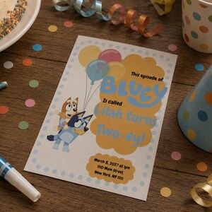 May include: A rectangular party invitation card featuring Bluey and Bingo characters holding balloons. The text reads: This episode of BLUEY is called Lilah turns Two-ey! March 8, 2027 at 1pm, 1110 Main Street, New York, NY 11111. The card has a light blue border.